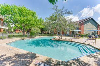 A pool surrounded by a fence and trees with a "No Diving" sign.